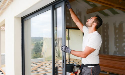 handsome young man installing bay window in a new house construction site